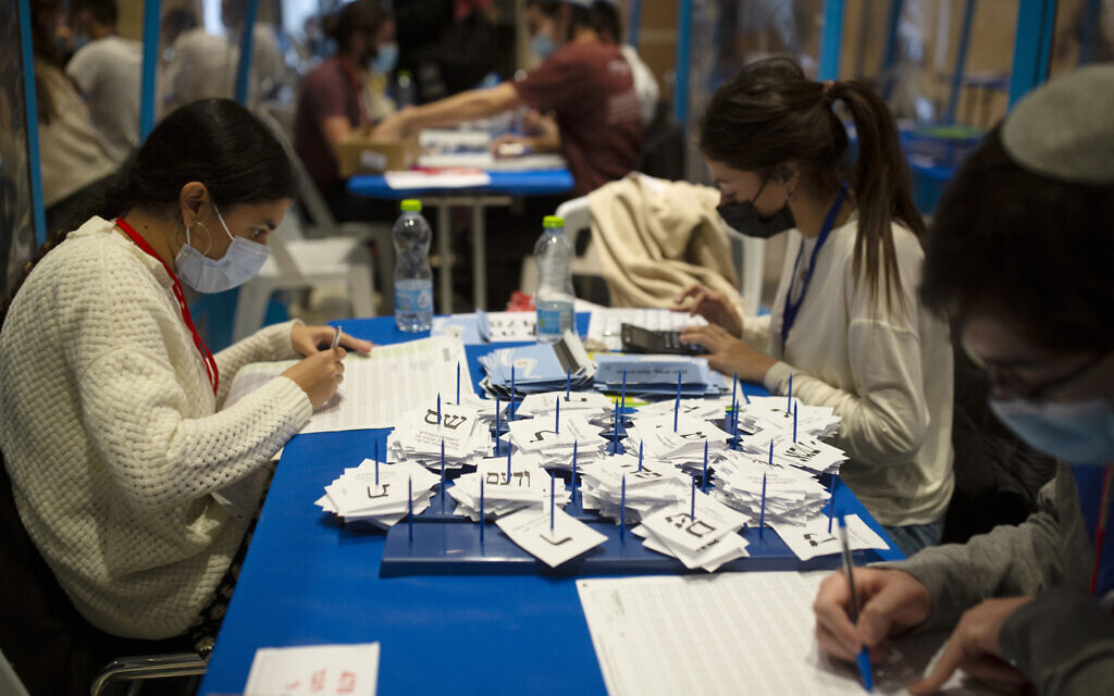 Workers count votes in Israel's national elections wearing and divided in groups by sheets of plastic masks to help curb the spread of the coronavirus, at the Knesset in Jerusalem, March 25, 2021. (AP Photo/Maya Alleruzzo)
