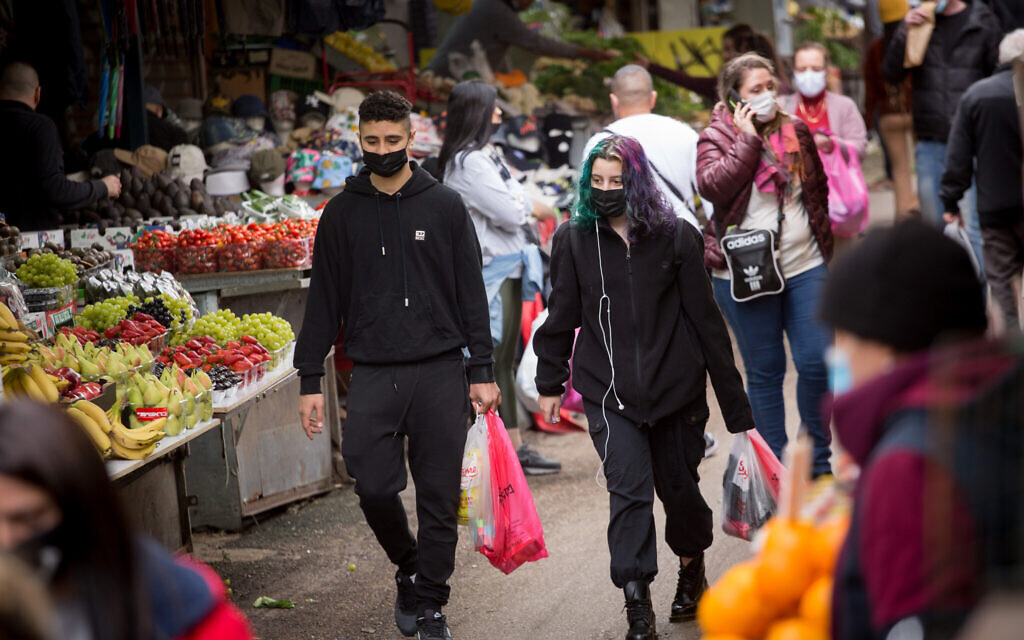 Illustrative: Israelis wear protective face masks as they shop at the Carmel market in Tel Aviv, on March 1, 2021. (Miriam Alster/FLASH90)