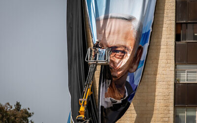 Israeli workers hang large election campaign posters of the Likud party, as part of the Likud election campaign, in Jerusalem on March 10, 2021 (Yonatan Sindel/Flash90)
