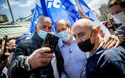Likud MK Nir Barkat takes a selfie with supporters during a campaign stop at Jerusalem's Mahane Yehuda on March 19, 2021. (Yonatan Sindel/Flash90)