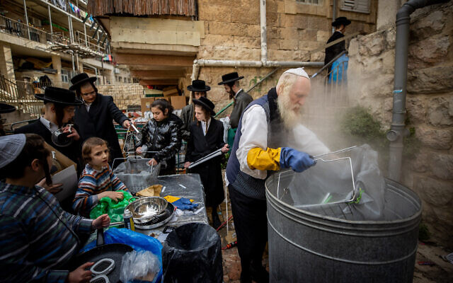 Ultra-Orthodox Jews dip cooking pots to rid any traces of leavening in preparation for the upcoming Passover holiday, in the ultra orthodox neighborhood of Mea Shearim in Jerusalem on March 25, 2021 (Yonatan Sindel/Flash90)