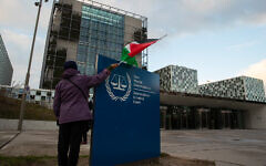 File - A demonstrators poses with a Palestinian flag outside the International Criminal Court (ICC) during a rally urging the court to prosecute Israel for alleged war crimes, in The Hague, Netherlands, November 29, 2019. (Peter Dejong/AP)