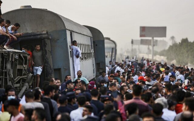 People gather by an overturned train carriage at the scene of a railway accident in the city of Toukh in Egypt's central Nile Delta province of Qalyubiya on April 18, 2021. (Ayman AREF / AFP)