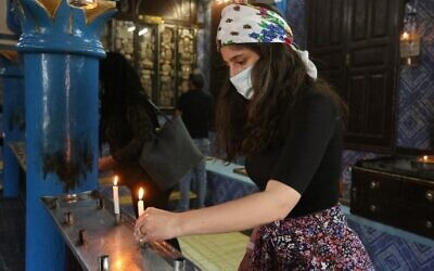 A Jewish pilgrim lights a candle on the first day of the annual pilgrimage to the Ghriba Synagogue, the oldest Jewish monument built in Africa, on April 26, 2021 in the Mediterranean Tunisian resort island of Djerba (Photo by FATHI NASRI / AFP)