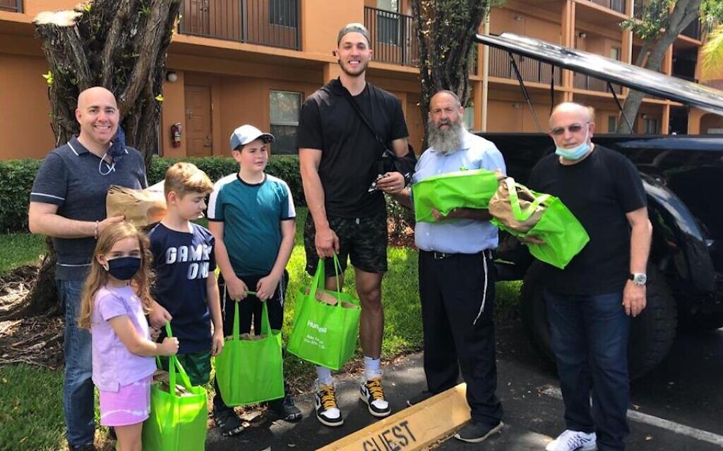 Meyers Leonard, center, distributes Passover dinners to Holocaust survivors and Jewish seniors in the Miami area with the help of Rabbi Pinny Andrusier, second from right. (Chabad of Southwest Broward via JTA)
