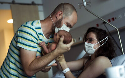 A father, wearing a face mask to protect against the spread of coronavirus, brings his newborn daughter her mother for breastfeeding in Liege, Belgium, June 26, 2020. (AP Photo/Francisco Seco)