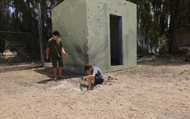 Israeli boys examine the site where a rocket fired from the Gaza Strip landed in Israel, April 24, 2021 (AP Photo/Tsafrir Abayov)