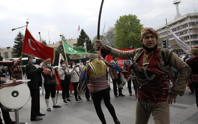 US soldiers stand guard on the rooftop of the United States embassy, in the background, as members of the Ankara club called Seymen dance in traditional clothes during a protest against a statement made by US President Joe Biden, in Ankara, Turkey, Monday, April 26, 2021. (AP Photo/Burhan Ozbilici)