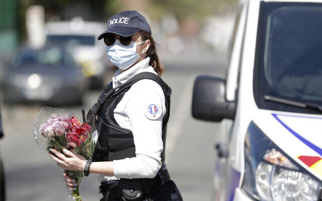 A police officer holds flowers given by residents to be taken down to the police station, where a police official had been stabbed to death on Friday in Rambouillet, south west of Paris, on April 26, 2021. (AP/ Thibault Camus)