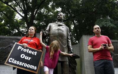 Illustrative image: Susan Foster, left, listens as her 7-year-old daughter Amelia plays on a Zebulon Baird Vance Statue at the Capitol as teachers and concerned citizens attend a Get Your Facts Straight! Rally in Raleigh, North Carolina, August 15, 2013. High school teacher Matthew Caggia, right, and others rallied to criticize the Republican legislature for public school policies approved this year and accuse them of misleading the public about their effects on the classroom. (AP Photo/Gerry Broome)