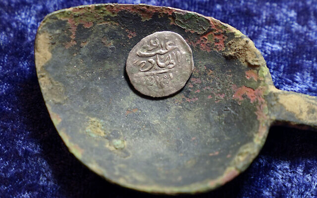 A 17th century Arabian silver coin that research shows was struck in 1693 in Yemen, rests in a 17th century brass spoon on a table, in Warwick, March 11, 2021 (AP Photo/Steven Senne)