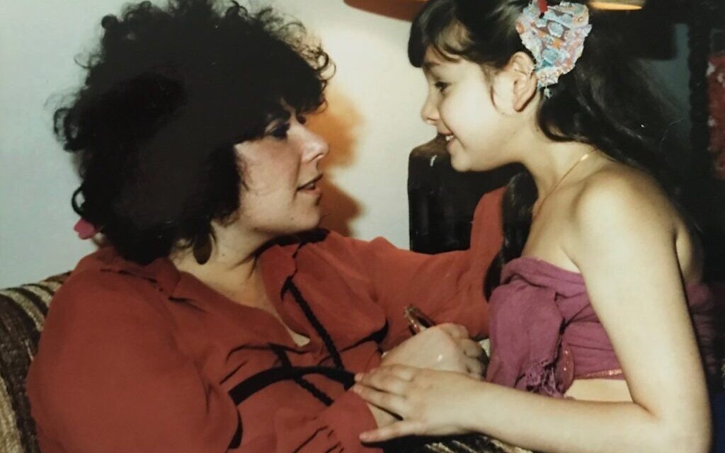 Ronit Plank with her mother in 1980, the first year after her mother returned from a year at Bhagwan Rajneesh Shree's ashram in Pune, India. Her mother wears the colors worn by the Rajneesh sannyasins (followers), and a mala (beaded necklace) with the photo of cult leader Bhagwan Shree Rajneesh. . (Courtesy)