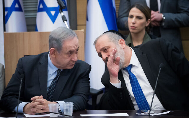 Illustrative: Then-Prime Minister Benjamin Netanyahu (left) speaks with Shas party chairman Aryeh Deri during a meeting in Jerusalem, March 4, 2020. (Yonatan Sindel/Flash90)