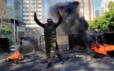 A man shouts slogans in front of burning tires and garbage containers during a protest against the increase in prices of consumer goods and the crash of the local currency, in Beirut, Lebanon, March 16, 2021. (AP Photo/Hussein Malla)