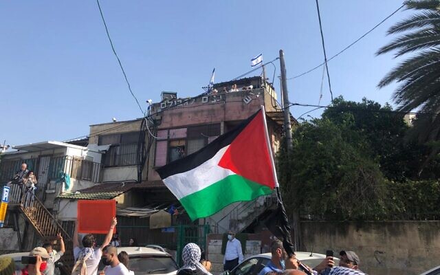 Palestinian demonstrators wave their national flag at a protest against the eviction of some Palestinians from Sheikh Jarrah in East Jerusalem on Friday, April 16, 2021 (Aaron Boxerman/The Times of Israel)