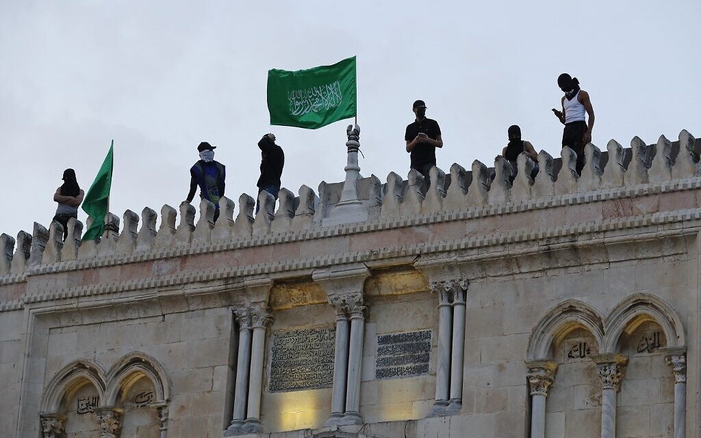 Palestinians place Hamas flags atop the Al-Aqsa mosque in Jerusalem's Old City on May 10, 2021. (Ahmad Gharabli/AFP)