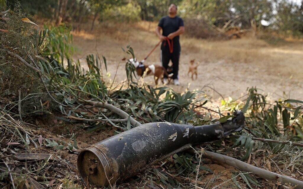 An Israeli man walks past the remains of a rocket fired by the Palestinian Hamas terror group from the Gaza Strip, which was destroyed by Israel's Iron Dome aerial defense system, on May 12, 2021 in Ashkelon (JACK GUEZ / AFP)