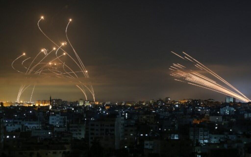 Rockets (l) are seen in the night sky fired towards Israel from Beit Lahia in the northern Gaza Strip on May 14, 2021, while Iron Dome interceptors rise to meet them (Photo by ANAS BABA / AFP)