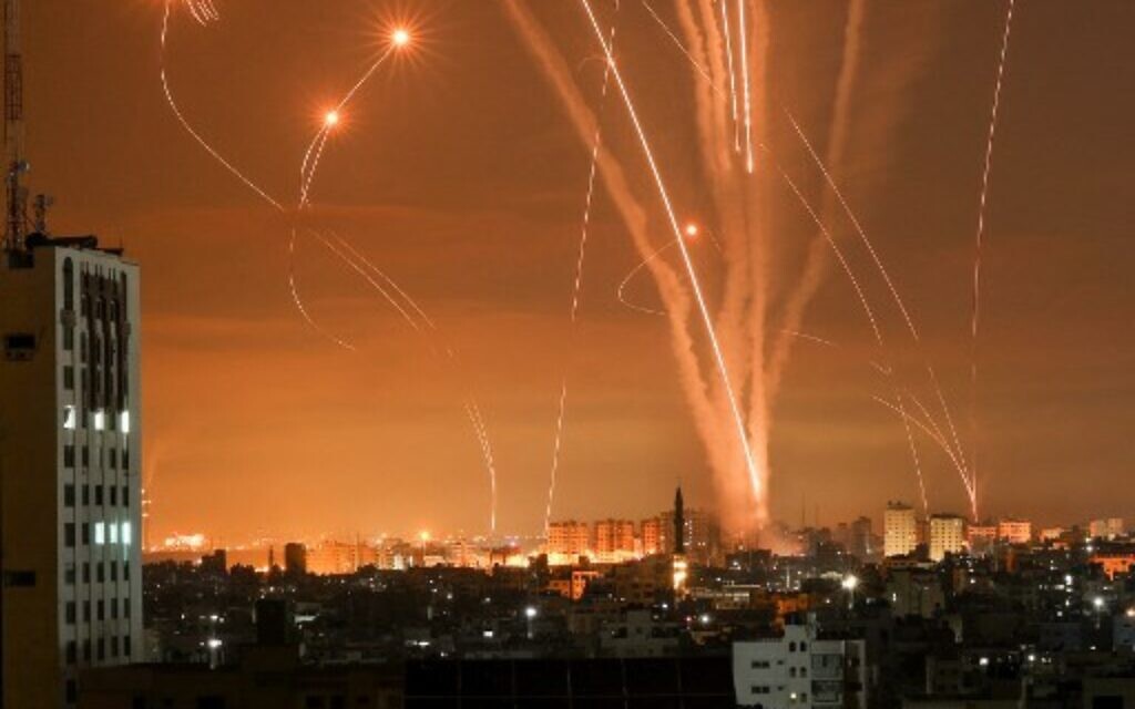 Hamas rockets light up the night sky as they are fired towards Israel from Beit Lahia in the northern Gaza Strip on May 14, 2021, while Israeli Iron Dome interceptors rise to meet them (Photo by MOHAMMED ABED / AFP)