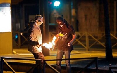 Illustrative: Palestinians light a Molotov cocktail during clashes with Israeli forces in the neighborhood of Shuafat in East Jerusalem, on May 14, 2021. (Ahmad Gharabli/AFP)