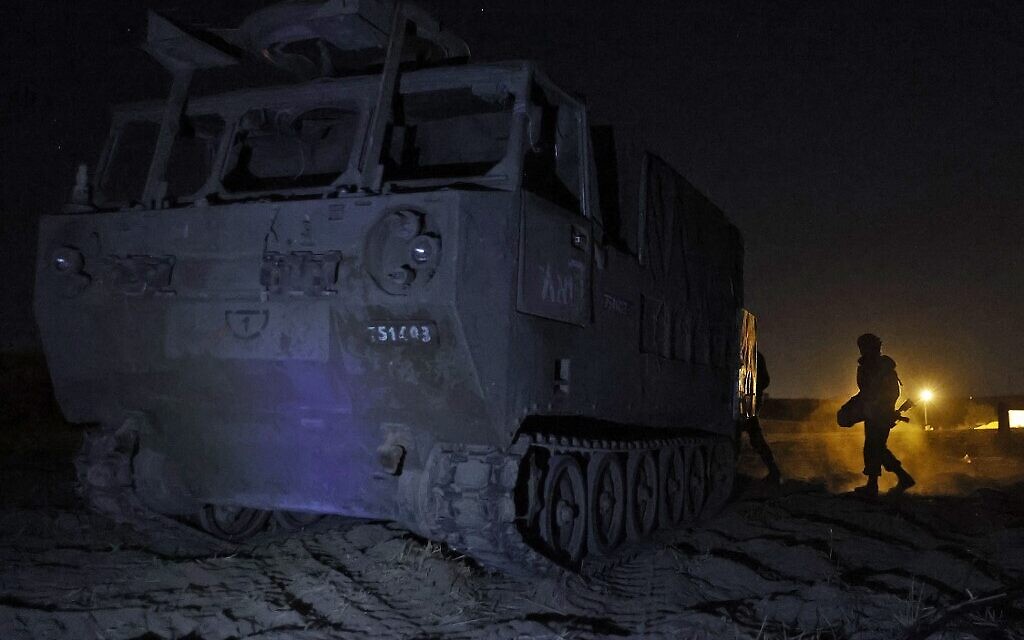 Israeli soldiers walk next to an ammunition transport vehicle at their position by the border with the Gaza Strip, on May 16, 2021. (JACK GUEZ / AFP)