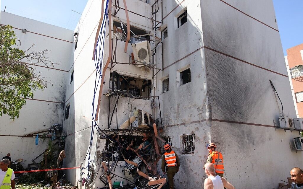 Israeli residents and rescue teams are pictured outside a building hit by a rocket launched from the Gaza Strip, in the southern city of Ashdod, on May 17, 2021.(Ahmad GHARABLI / AFP)