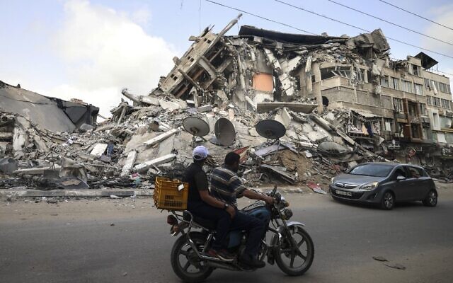 Palestinians ride past the Al-Shuruq building, destroyed by an Israeli air strike, in Gaza City on May 21, 2021, after a ceasefire was agreed between Israel and Hamas (MAHMUD HAMS / AFP)