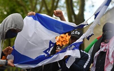 Pro-Palestinian activists and supporters burn an Israeli flag as they demonstrate in support of the Palestinian cause outside the Israeli Embassy in central London on May 22, 2021. (Justin Tallis/AFP)