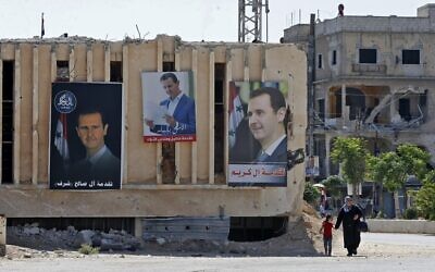 Portraits of Syrian President Bashar al-Assad are hung on buildings at a polling station in Douma, near the capital Damascus, on May 26, 2021. (Louai Beshara/AFP)