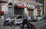 A man passes by cars torched after a night of violence between Israeli Arab protesters and Israeli police in the mixed Arab-Jewish town of Lod, central Israel, on Tuesday, May 11, 2021. (AP Photo/Heidi Levine)