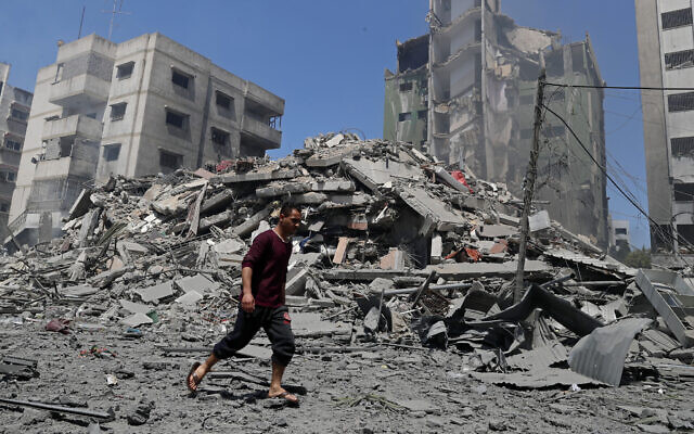 A man walks past the rubble of the Yazegi residential building that was destroyed by an Israeli airstrike, in Gaza City, Sunday, May 16, 2021. (AP Photo/Adel Hana)