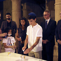 Israeli's Ambassador to the United Arab Emirates, Eitan Na'eh, right, and German Ambassador in UAE, Peter Fischer, second right, watch a candlelight ceremony at an exhibition commemorating the Holocaust, in Dubai, United Arab Emirates, May 26, 2021. (Kamran Jebreili/AP)