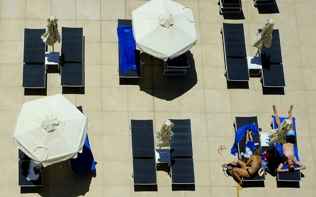 A family on vacations lounges at the pool of Nissi Blue hotel in southeast resort of Ayia Napa, in the eastern Mediterranean island of Cyprus, on May 22, 2021. (AP Photo/Petros Karadjias)