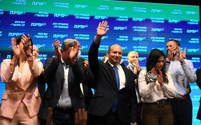 Yamina chair Naftali Bennett (C) and party members seen with supporters at a party event in Petah Tikva after election day, March 23, 2021. (Avi Dishi/Flash90)