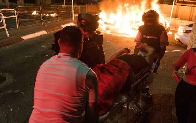 Medics evacuate an injured man during clashes between Arab and Jews in Acre, northern Israel, May 12, 2021. (Roni Ofer/Flash90)