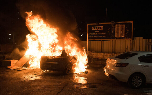 A car is set on fire during clashes between Arab and Jews in Acre, northern Israel, May 12, 2021 (Roni Ofer/Flash90)