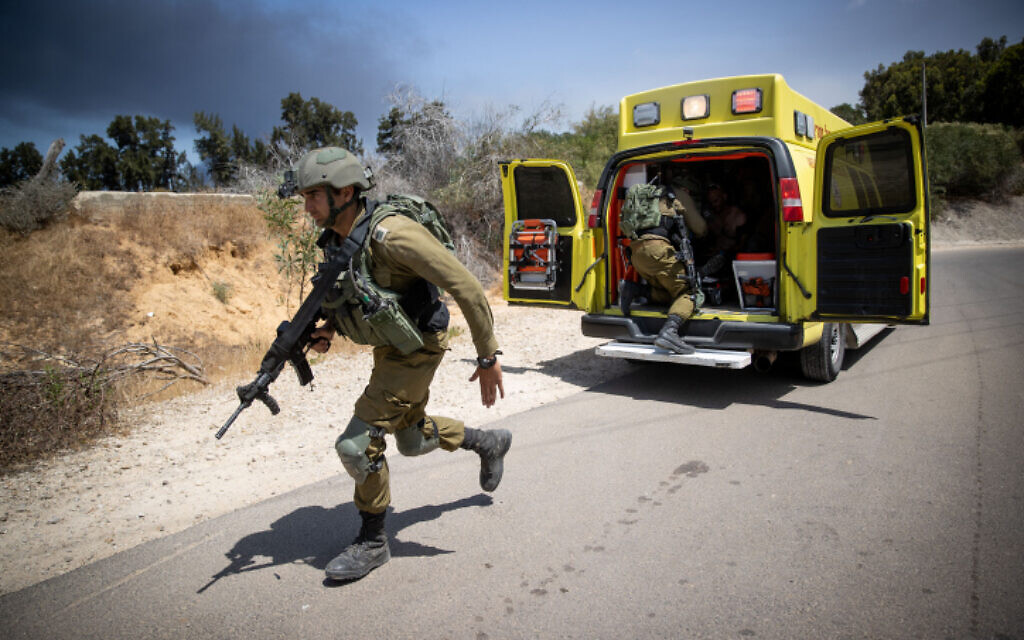 Israeli soldiers near the site of where a jeep went up in flames, injuring 2 and killing one, following a direct hit by a missile fired from Gaza, in Netiv Ha'asara, May 12, 2021 (Yonatan Sindel/Flash90)