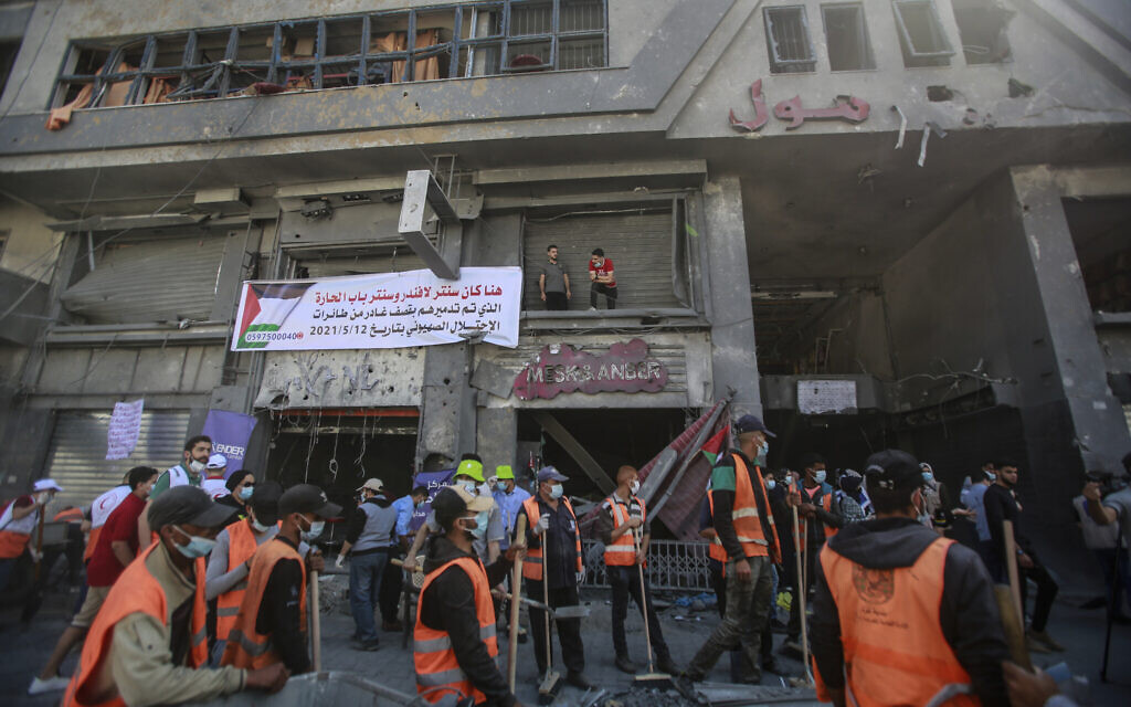 Palestinian volunteers clear the rubble at a street in Gaza City, after it was hit by Israeli airstrikes during Operation Guardian of the Walls, May 23, 2021. (Atia Mohammed/Flash90)