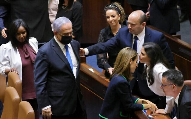 Defeated prime minister Benjamin Netanyahu walks away after briefly shaking hands with new Prime Minister Naftali Bennett, after the Knesset voted confidence in Bennett's coalition by 60-59 votes, June 13, 2021 (Emmanuel Dunand / AFP)