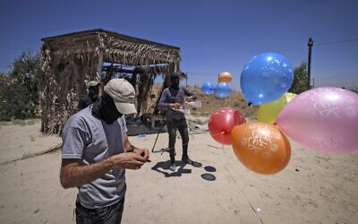 Masked Palestinian Islamic Jihad terrorists prepare incendiary balloons east of Gaza city, to launch across the border fence towards Israel on June 15, 2021. (MAHMUD HAMS / AFP)