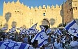Nationalist Israel Jews wave Israeli flags as they march outside the Damascus Gate to Jerusalem's Old City, on June 15, 2021. (Ahmad Gharabli/AFP)