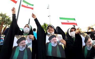 Supporters of Iranian ultraconservative presidential candidate Ebrahim Raisi carry posters bearing his portrait and wave national flags as they attend a rally in the capital Tehran, on June 16, 2021, ahead of the Islamic republic's June 18 presidential election.  (Photo by ATTA KENARE / AFP)