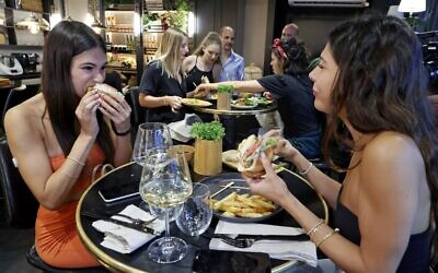 Diners eat burgers made with "cultured chicken" meat at a restaurant adjacent to the SuperMeat production site in the central Israeli town of Ness Ziona on June 18, 2021 (JACK GUEZ / AFP)