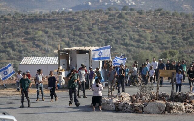 Israeli settlers march with flags at the illegal West Bank outpost of Evyatar on June 21, 2021. (Ahmad Gharabli/AFP)