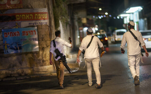 Jews walk through the street with guns in the mixed Arab-Jewish town of Lod, central Israel, May 28, 2021, in the wake of recent clashes between the two groups. (AP Photo/David Goldman)