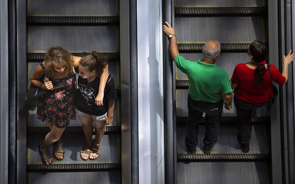 People ride an escalator at a shopping mall after restrictions requiring face masks indoors was lifted, in Tel Aviv, Tuesday, June 15, 2021. Israel lifted one of its last coronavirus restrictions Tuesday following a highly successful vaccination campaign. (AP Photo/Oded Balilty)