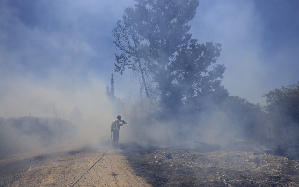 An Israeli firefighter attempts to extinguish a fire caused by an incendiary balloon launched by Palestinians from the Gaza Strip, on the Israel-Gaza border, Israel, Tuesday, June 15, 2021. (AP Photo/Tsafrir Abayov)