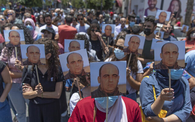 Angry demonstrators carry pictures of Nizar Banat, an outspoken critic of the Palestinian Authority, and chant anti-PA slogans during a rally protesting his death, in the West Bank city of Ramallah, on June 24, 2021. (AP Photo/Nasser Nasser)
