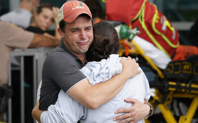 A couple embrace as they wait for news of survivors from a condominium that collapsed, Thursday, June 24, 2021 in Surfside, Fla. Dozens of survivors were pulled out, and rescuers continue to look for more. (AP Photo/Marta Lavandier)