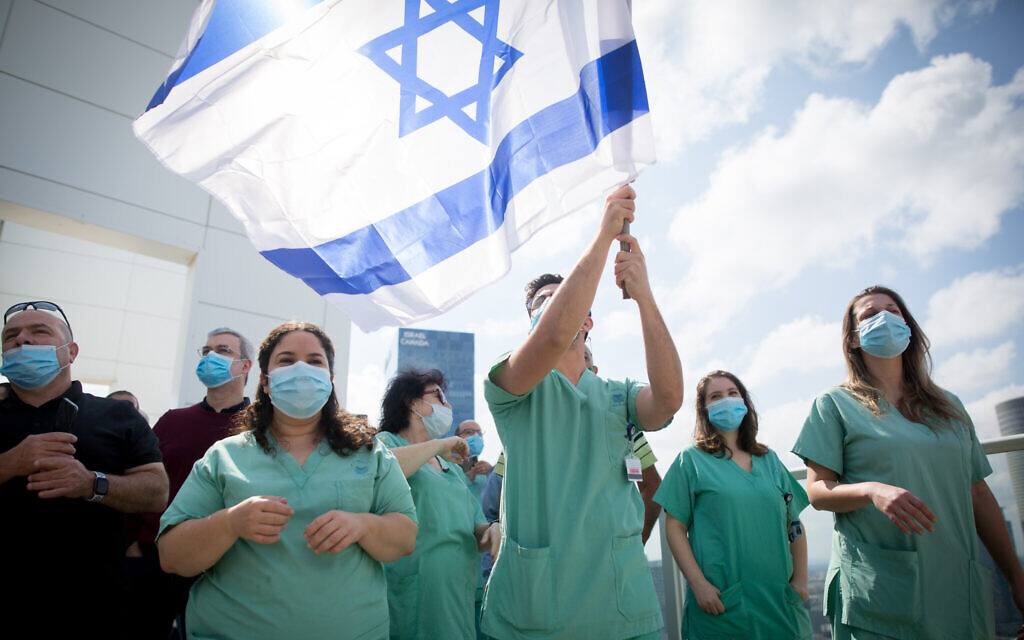 Israeli medical staff cheer an Israeli airforce acrobatic team flying over Ichilov hospital in Tel Aviv on Israel's 72nd Independence Day, April 29, 2020 (Miriam Alster/Flash90)